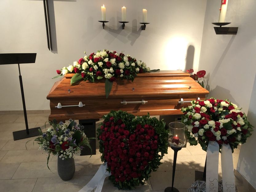 Sargaufbahrung mit Blumen und Kerzen