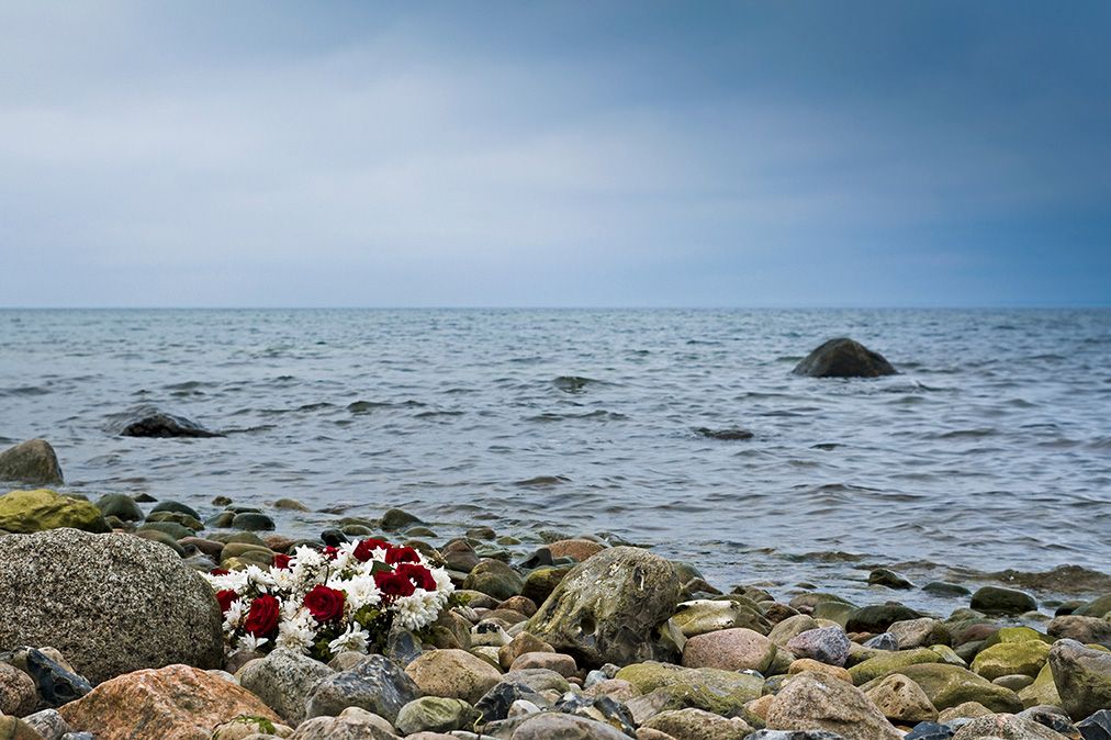 Blumenkranz liegt auf Steinen am Meer